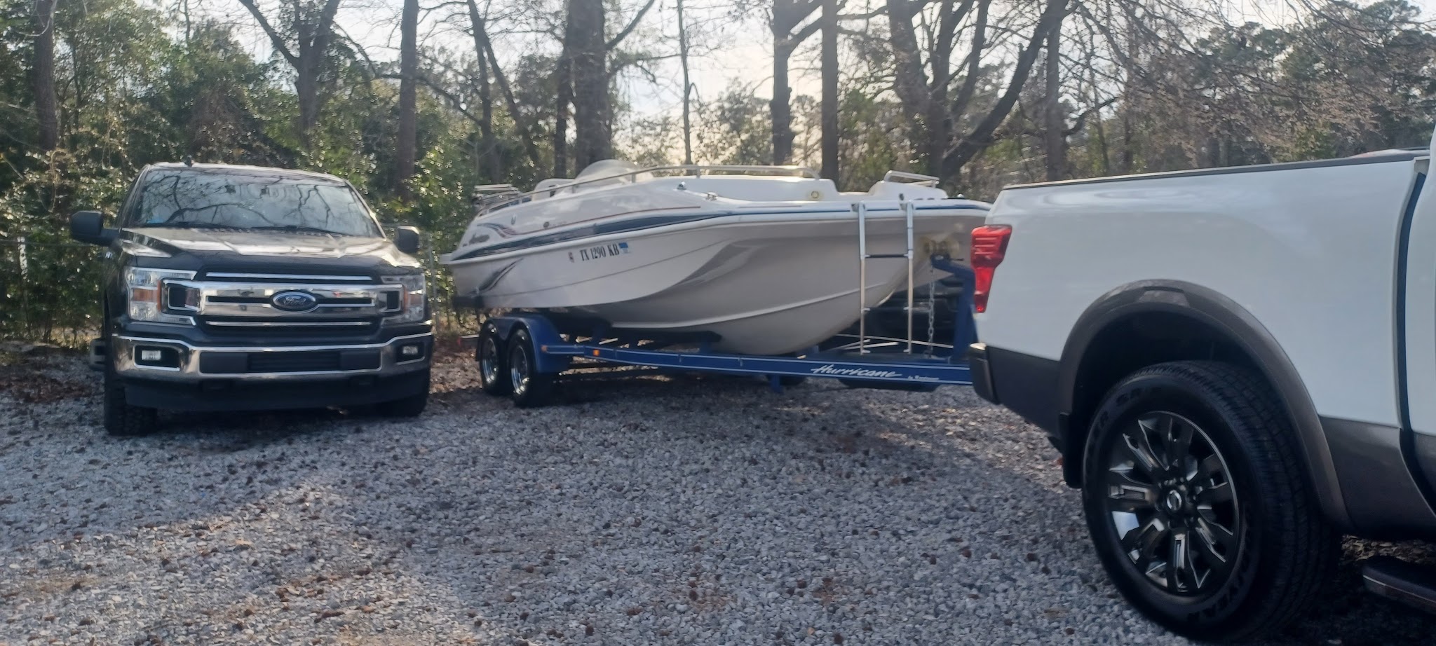 Two pickup trucks and a boat on a trailer